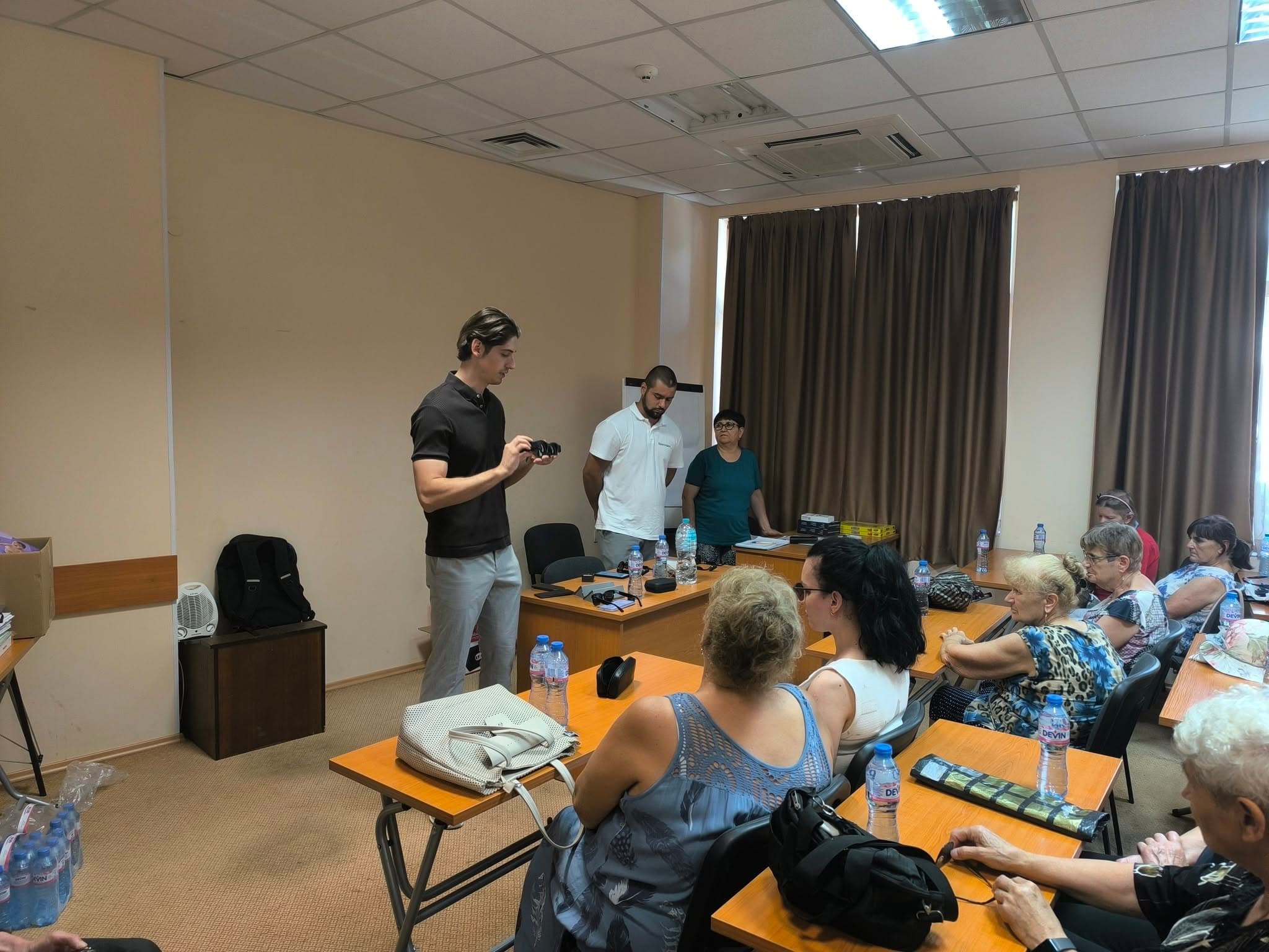 A SparkVision representative shows the Glasses 2 to attendees seated in a meeting room